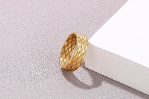 Macro detail of a gold-plated stainless steel wide ring featuring a quilted fish-scale pattern