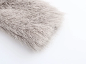 Detailed view of plush grey faux fur texture on a stylish long winter coat for women