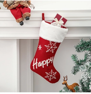 Close-up of red Happy Christmas stocking with white snowflake and gift box by a fireplace