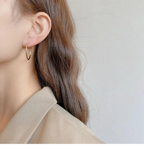 Minimalist gold hoop earring on model showing sleek metallic texture and style