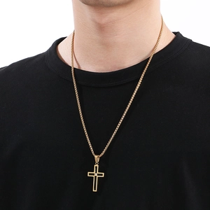Close-up of a gold cross pendant necklace with black inlay worn by a male model