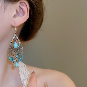 Detailed view of bohemian blue crystal teardrop tassel earrings worn by a model