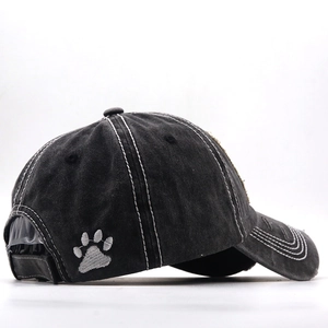 Detailed close-up of distressed cotton baseball cap with gray paw embroidery and contrast stitching