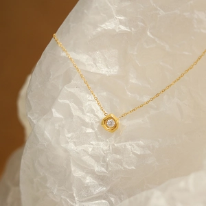 Macro view of gold hexagonal geometric pendant with a clear zircon on a fine chain