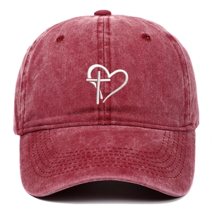 Close-up of white heart and cross embroidery on a burgundy washed cotton baseball cap