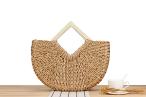 Detail of straw woven handbag with gold thread texture and geometric wooden handle