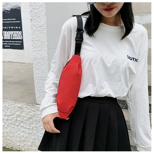 Outdoor close-up of a red canvas fanny pack with adjustable black strap on white T-shirt