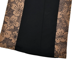 Detail of black jumpsuit hem featuring contrast beige floral pattern panels and side stitching