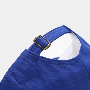 Detailed macro view of the royal blue cotton baseball cap with bronze metal adjustment buckle