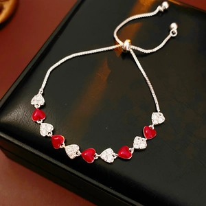 Detail of silver heart bracelet with red enamel and white zircon on leather box