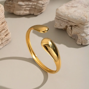 Minimalist gold teardrop open bangle in polished stainless steel on stone aesthetic