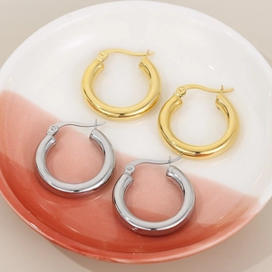 Polished gold and silver solid stainless steel hoop earrings set on a ceramic dish