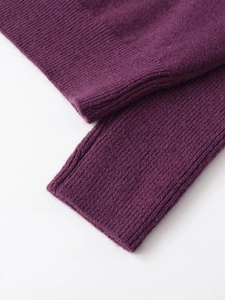 Detail view of purple ribbed knit texture showing soft wool fabric on sleeve cuffs