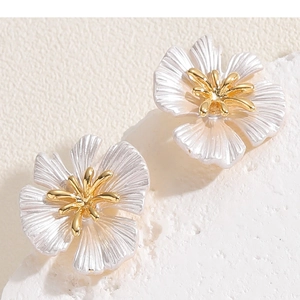 Macro detail of camellia flower earrings with pearl white petals and golden core