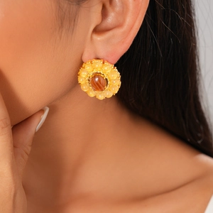 Close-up of vintage gold stud earring with amber resin center and yellow bead halo