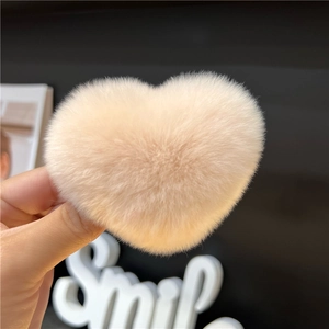 Macro view of beige heart-shaped faux rabbit fur hair clip with soft plush texture