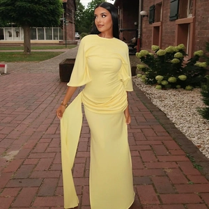 Detail of light yellow backless maxi dress with tiered draped ribbons and cape sleeves