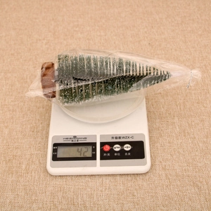 Detailed view of a mini snow-flocked Christmas tree with wooden base on a scale weighing 42g