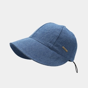 Detail view of washed denim sun hat featuring a gold metal logo plate and drawstring