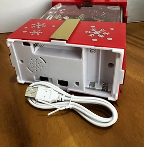 Detail of red Christmas snow globe base showing USB power port and battery compartment