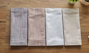 Macro view of textured linen napkins in four muted colors on a rustic wooden table surface