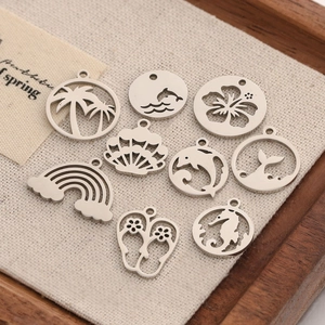 Detail of stainless steel ocean themed charms like dolphins and palm trees on linen