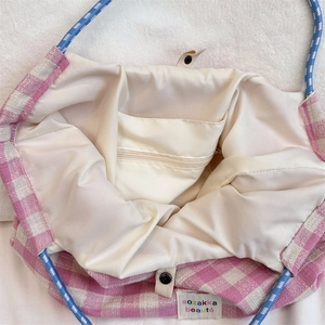 Detail of pink plaid tote bag featuring a zip pocket, satin lining, and snap closure
