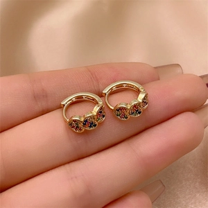 Detail of hand-held gold heart hoop earrings with colorful pavé cubic zirconia