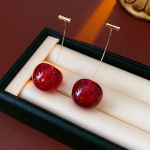 Deep red resin cherry drop earrings with gold glitter and metallic stems on black display