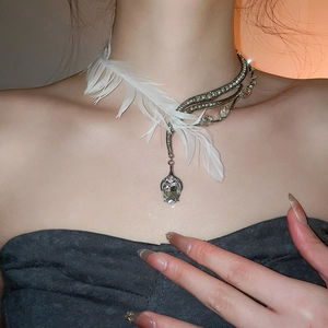 Détail d'un collier asymétrique avec plumes blanches et pendentif en cristal en goutte