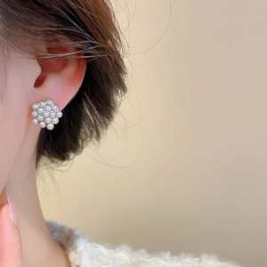 Close-up of minimalist silver needle pearl stud earrings worn on a model's ear