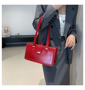 Chic red shiny leather shoulder bag worn over a grey blazer for a stylish vintage look