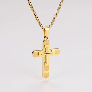 Macro view of gold double-layer cross pendant with textured finish on box chain