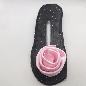 Detail of pink satin rose hair bun maker tool with black silver dot fabric texture