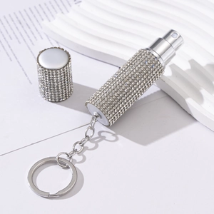 Detailed macro of a silver rhinestone-studded spray perfume bottle with keychain