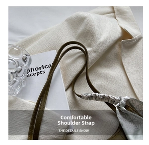 Detail of olive green leather shoulder strap with elegant geometric silk scarf wrap