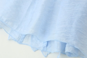 Close-up of light blue sleeveless shirt hem with textured fabric and ruffled edges