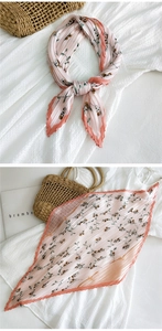 Dettaglio di un foulard quadrato a pieghe floreale in chiffon rosa con bordo arancio
