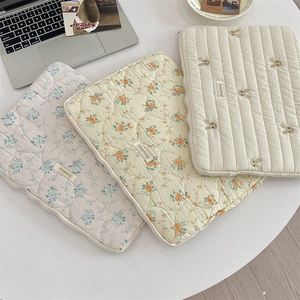 Close-up of quilted floral and rabbit embroidered laptop sleeves with zipper closure