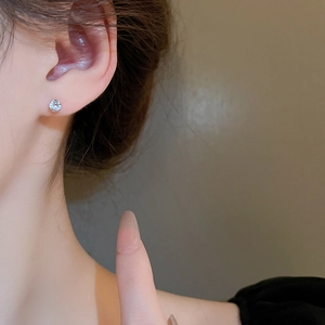 Close-up of a silver stud earring with a round-cut cubic zirconia worn on an earlobe