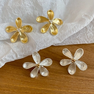 Dettaglio di orecchini a fiore con trama metallica spazzolata in oro e argento