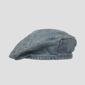 Detail of light blue denim beret featuring orange contrast stitching and side pocket