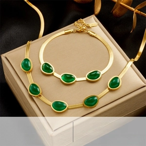 Detailed view of emerald green stone pendant on gold snake chain jewelry set