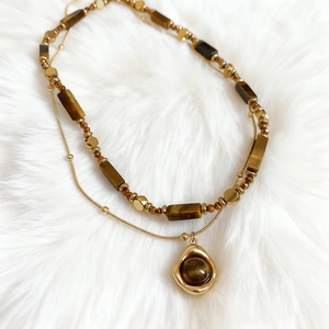 Vintage layered tiger eye beaded necklace with golden pendant on white fur background
