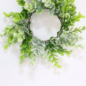Detailed view of artificial eucalyptus candle wreath with frosted green leaves and vine base