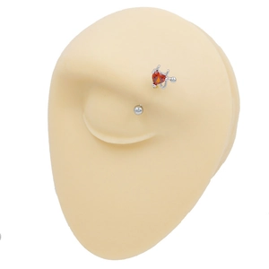 Close-up of silver eyebrow piercing featuring a red devil heart design with horns