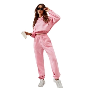 Pink two-piece sports set with cropped drawstring hoodie and matching joggers on white background