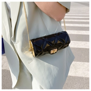 Fashionable black quilted cylinder jelly bag with gold chain strap worn by a model