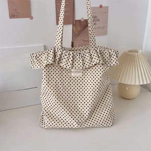 Close-up of beige polka dot canvas tote bag with ruffle trim and Japanese style label