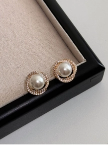 Detailed shot of elegant pearl earrings with sparkling zircon halos in a jewelry box